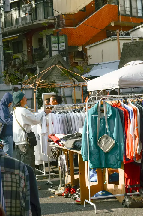 蔦の絡まる建物を背にした白いテントのブースと、商品を選ぶ来場者