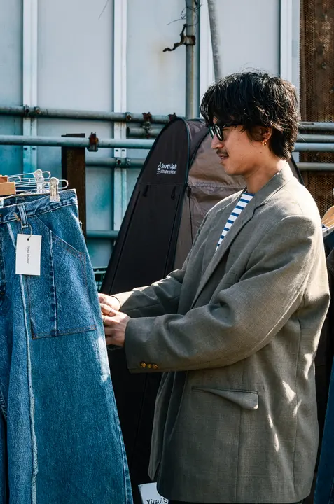 ハンガーに掛かったデニムを手に取って見ている来場者