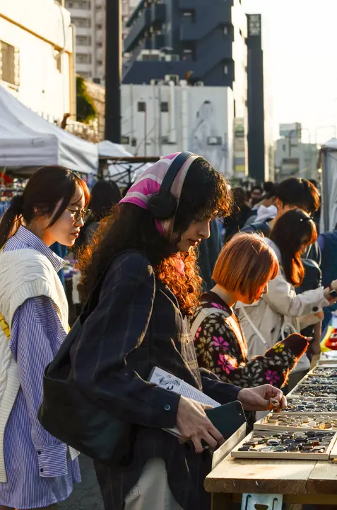 人が行き交う通り沿いのブースで、アクセサリーを見比べる来場者