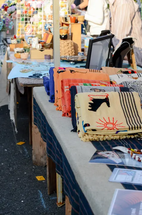 太陽や馬の刺繍が入った布ものが、色ごとに重ねて並べられた台