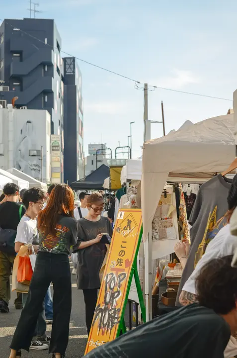 「POP UP STORE」の立て看板が出たテントと、通りを行き交う来場者